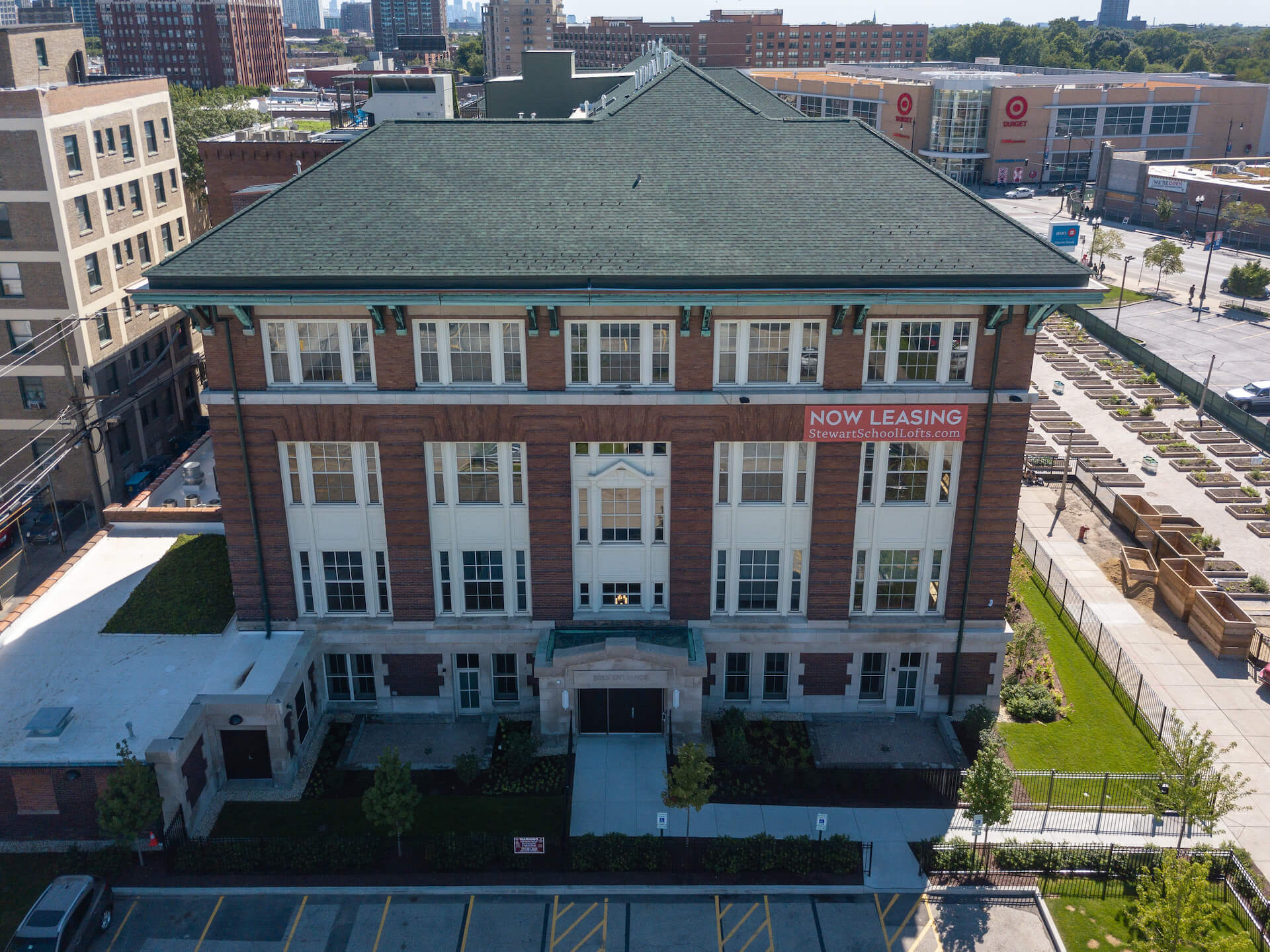 Exterior, aerial view of Stewart School Lofts building, grass courtyard, and surrounding urban area.