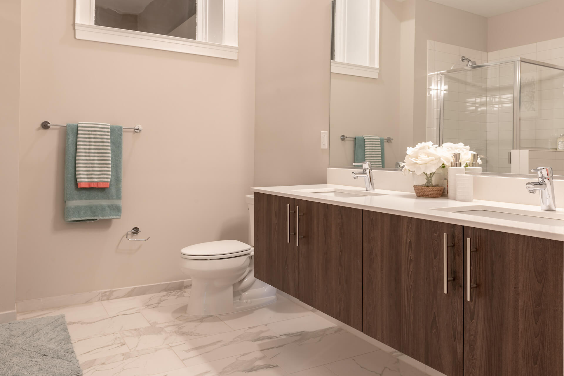 Spacious bathroom with custom double vanity, bathtub, glass shower, and marble style tile.