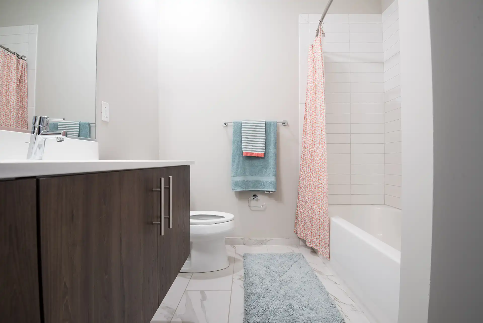 Bathroom with sink, toilet, shower, custom cabinetry, and designer tile.