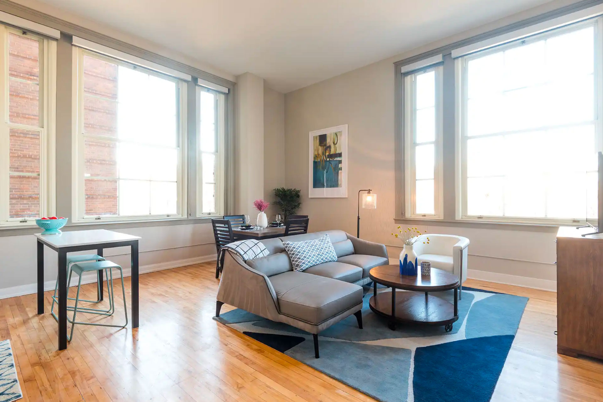 Bright living room with wood style flooring, large windows, and decorated with contemporary furniture.